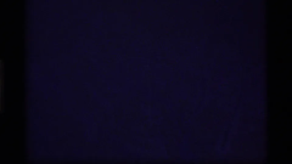 Dark opening 8mm frame from the Glacier Bay clip, with faint blue-purple exposure and heavy black film edges.