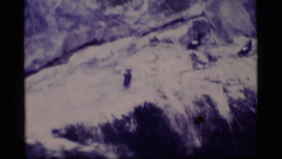 Rocky shoreline detail appears in soft, purple-tinted 1977 8mm footage from Glacier Bay, Alaska.