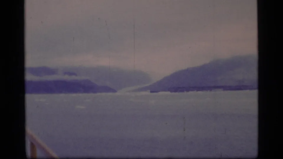 A wide 8mm view of Glacier Bay shows gray water, low clouds, and distant mountain forms in muted 1970s color.
