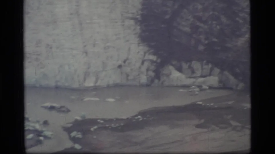 Final 8mm frame from Glacier Bay showing the glacier face, shadowed shore, still water, and small ice floes.