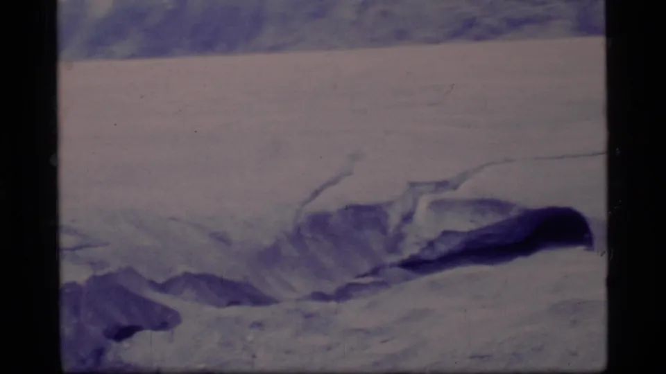 The 8mm frame emphasizes Glacier Bay ice, a dark crevasse, and distant mountainous terrain; any person is not clearly visible here.