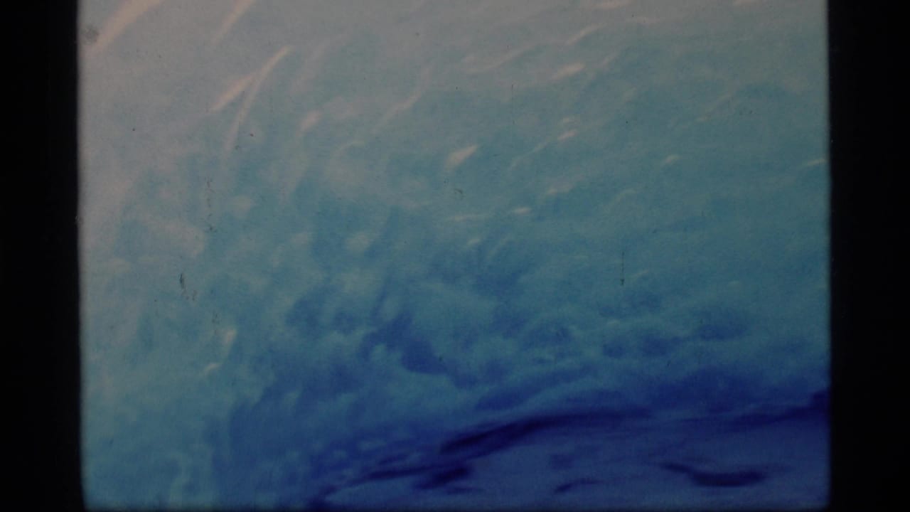 Blue glacier ice surface seen through an 8mm frame with dark borders.