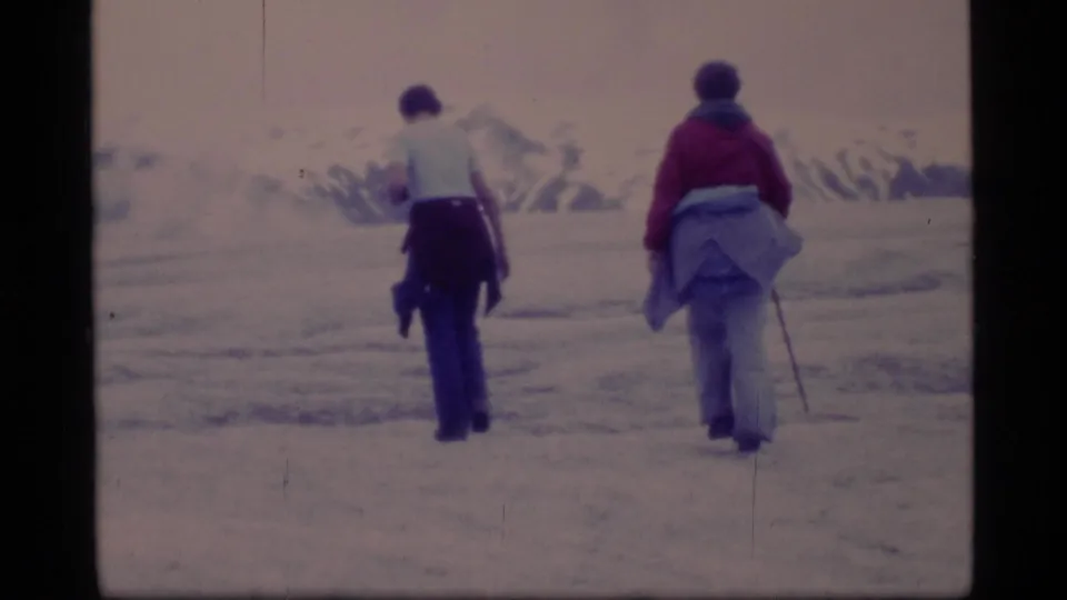 Two figures seen from behind walk across the Glacier Bay ice field, framed by soft 1970s 8mm color.