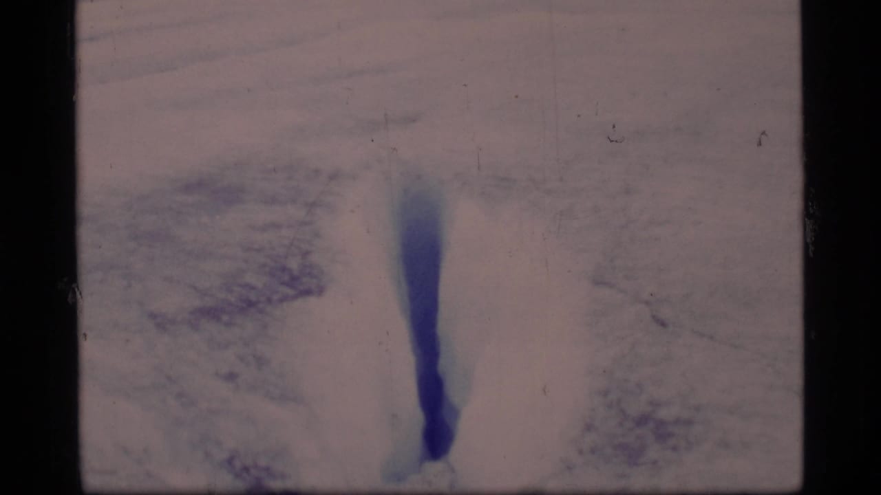 A close view of a narrow blue crevasse in Glacier Bay snow and ice, recorded with soft 8mm exposure and visible film borders.