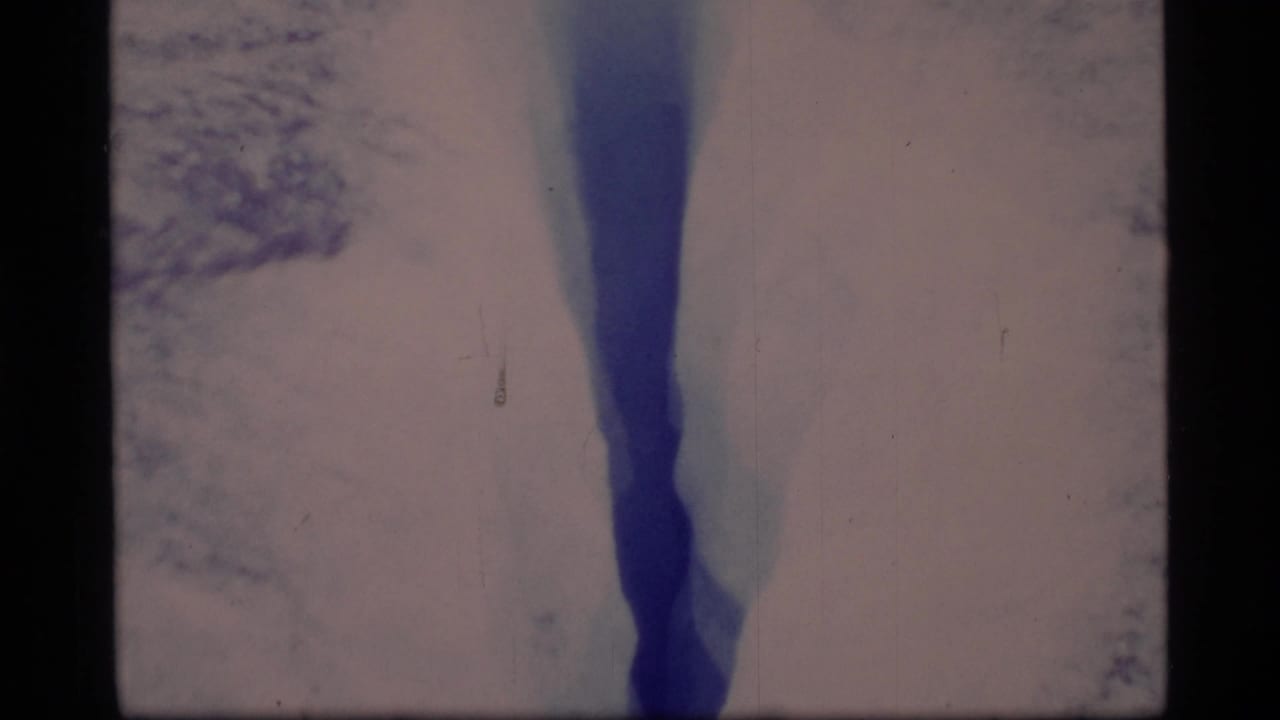1977 Glacier Bay footage showing a dark blue ice crevasse bordered by pale snow and glacier surface.