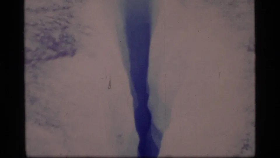 1977 Glacier Bay footage showing a dark blue ice crevasse bordered by pale snow and glacier surface.