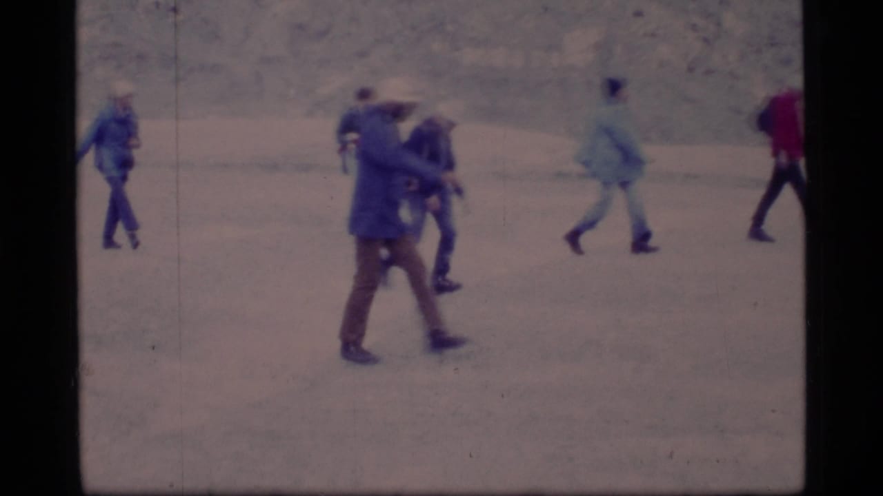 1977 Glacier Bay footage shows adults in heavy outerwear walking and interacting on a snowy surface.