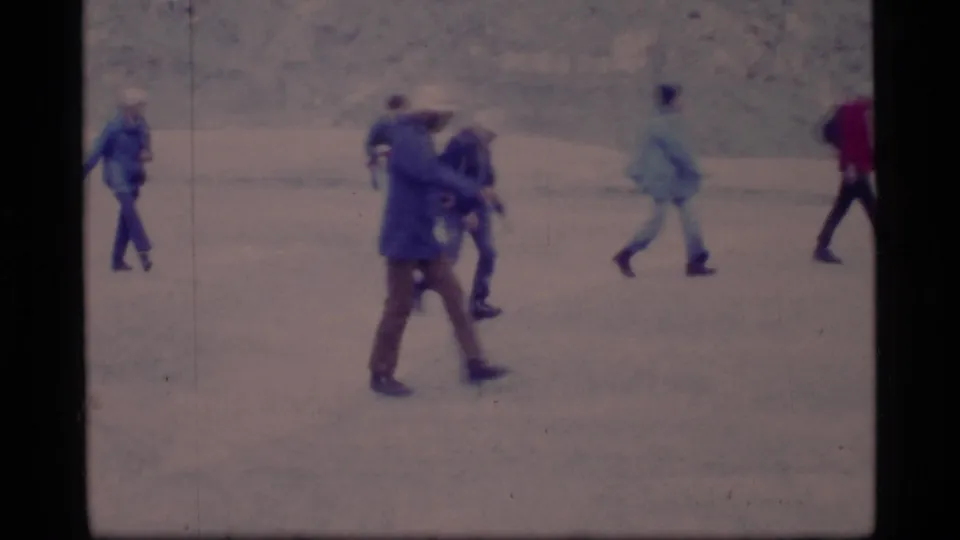 1977 Glacier Bay footage shows adults in heavy outerwear walking and interacting on a snowy surface.
