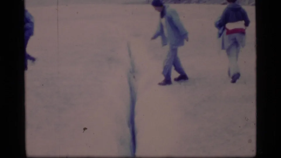 A Glacier Bay home-movie frame from 1977 shows bundled adults moving across snow with visible 8mm film wear.