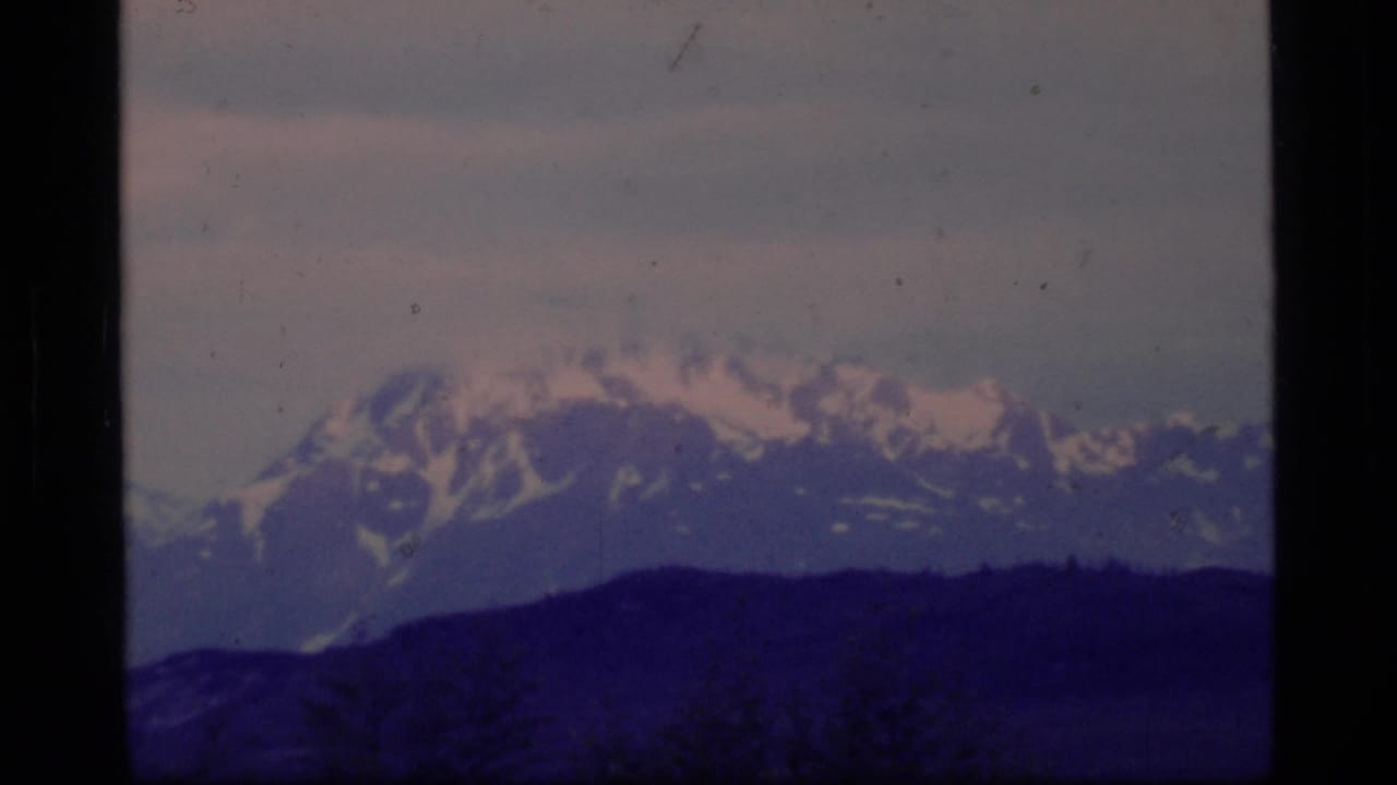 Distant snow-capped mountains in Glacier Bay, Alaska, seen through soft 1977 8mm film framing.