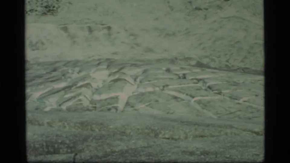 1977 Glacier Bay close view of crevassed glacier surface and rough ice texture, with distant terrain softened by film grain.