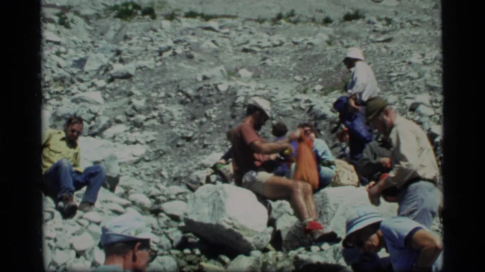 1977 Glacier Bay hiking scene with adults resting among boulders on a bright rocky mountainside.