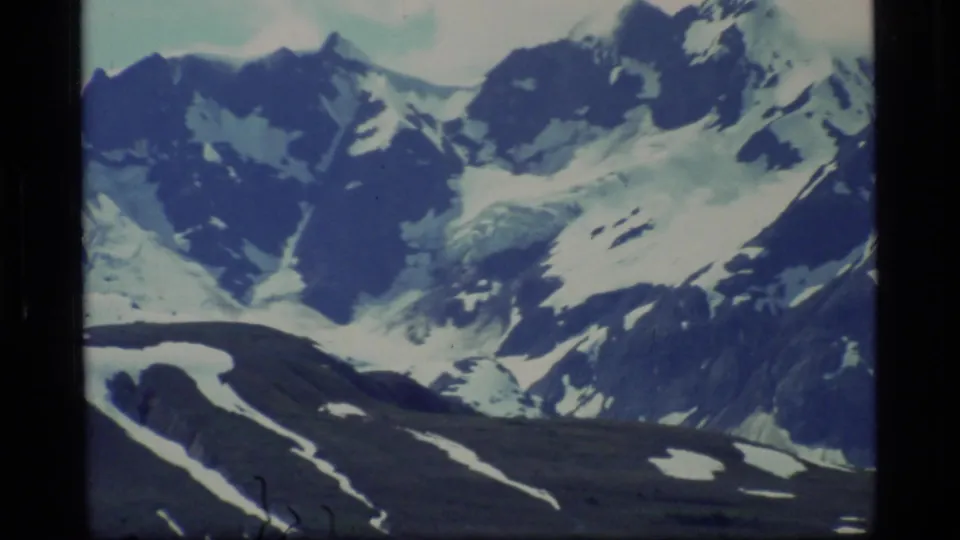 1977 8mm Glacier Bay landscape with a close distant view of rugged snow-covered mountain slopes and glacier-like ice.