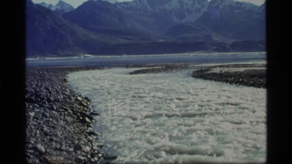 1977 Glacier Bay, Alaska 8mm frame with a broad textured river foreground and dark mountain range in the distance.