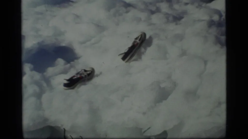 1977 Glacier Bay frame showing two separated sneakers on snow or ice in a handheld 8mm view.