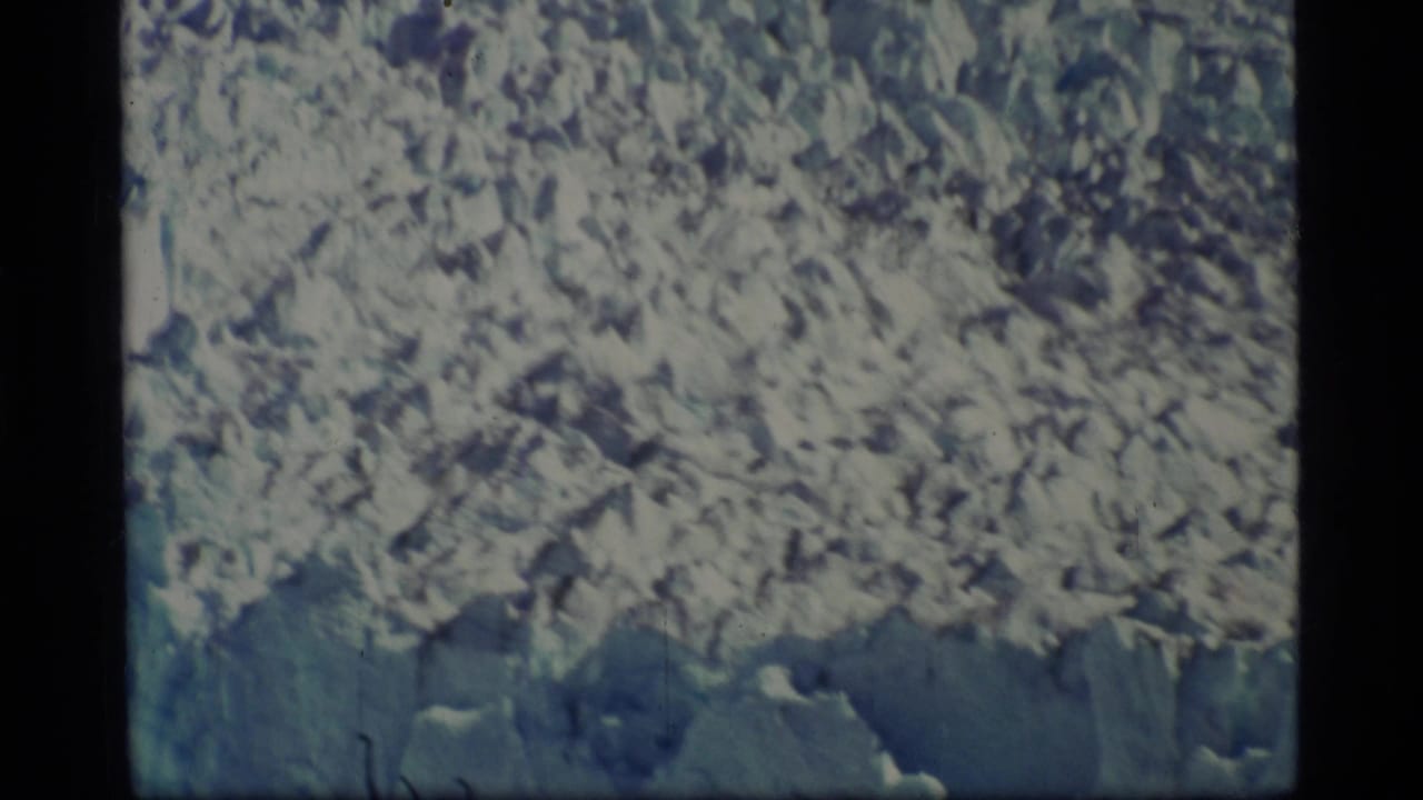1977 8mm Glacier Bay footage showing a close, soft-focused view of pale glacial ice and rough frozen texture.