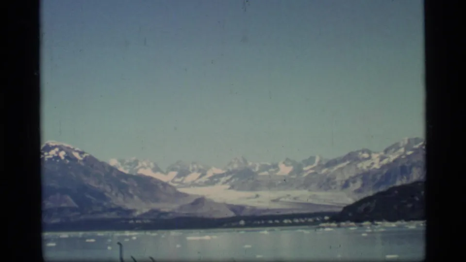 Wide 1977 Glacier Bay landscape showing icy water, a distant glacier or icefield, surrounding mountains, and a broad pale sky.