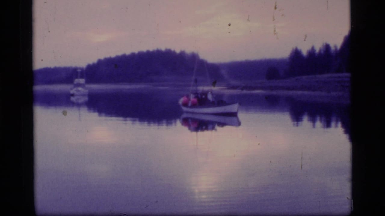 1977 8mm Glacier Bay view of a small boat with occupants on still water beneath a purple dusk sky.