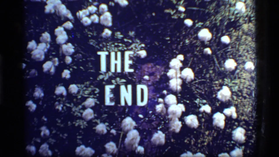 1977 8mm end card from the Glacier Bay reel, with bold white THE END lettering surrounded by white flowers and greenery.