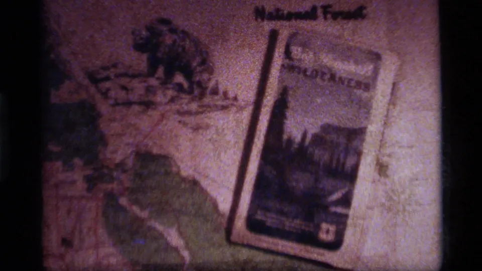 Soft 8mm close-up of Montana trip-planning papers, including National Forest text and a wilderness brochure.