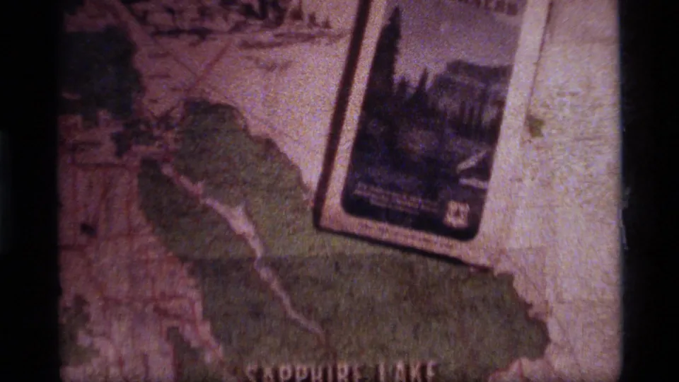 Final 8mm frame from the Sapphire Lake, Montana planning clip, showing a brochure over map detail and green shaded terrain.