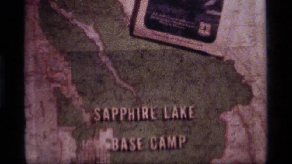 Faded 8mm view of a map title reading Sapphire Lake Base Camp, with a small photograph or card visible near the upper edge.
