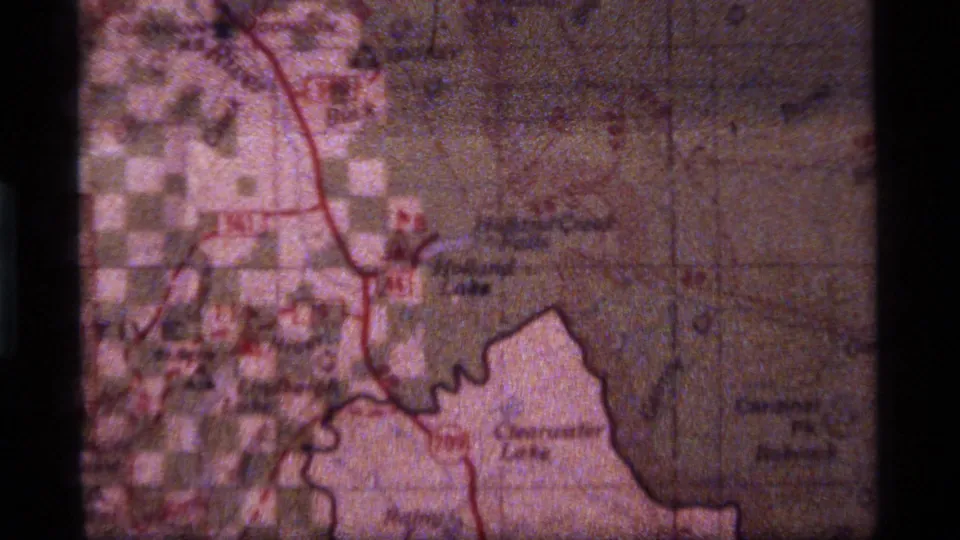 8mm frame of the Sapphire Lake and Peacock map context, showing a red route, pale pink mapped area, faint labels, and visible film grain.