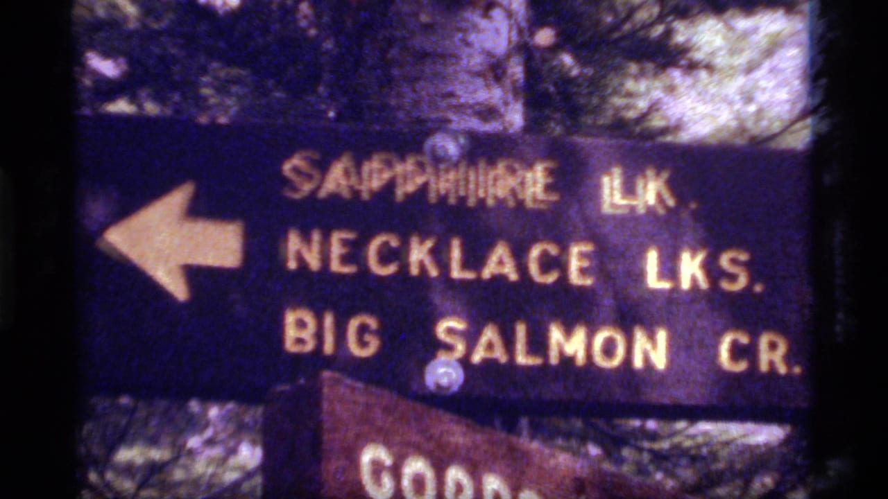 Close view of the same trail sign with a partial lower wooden sign below it.