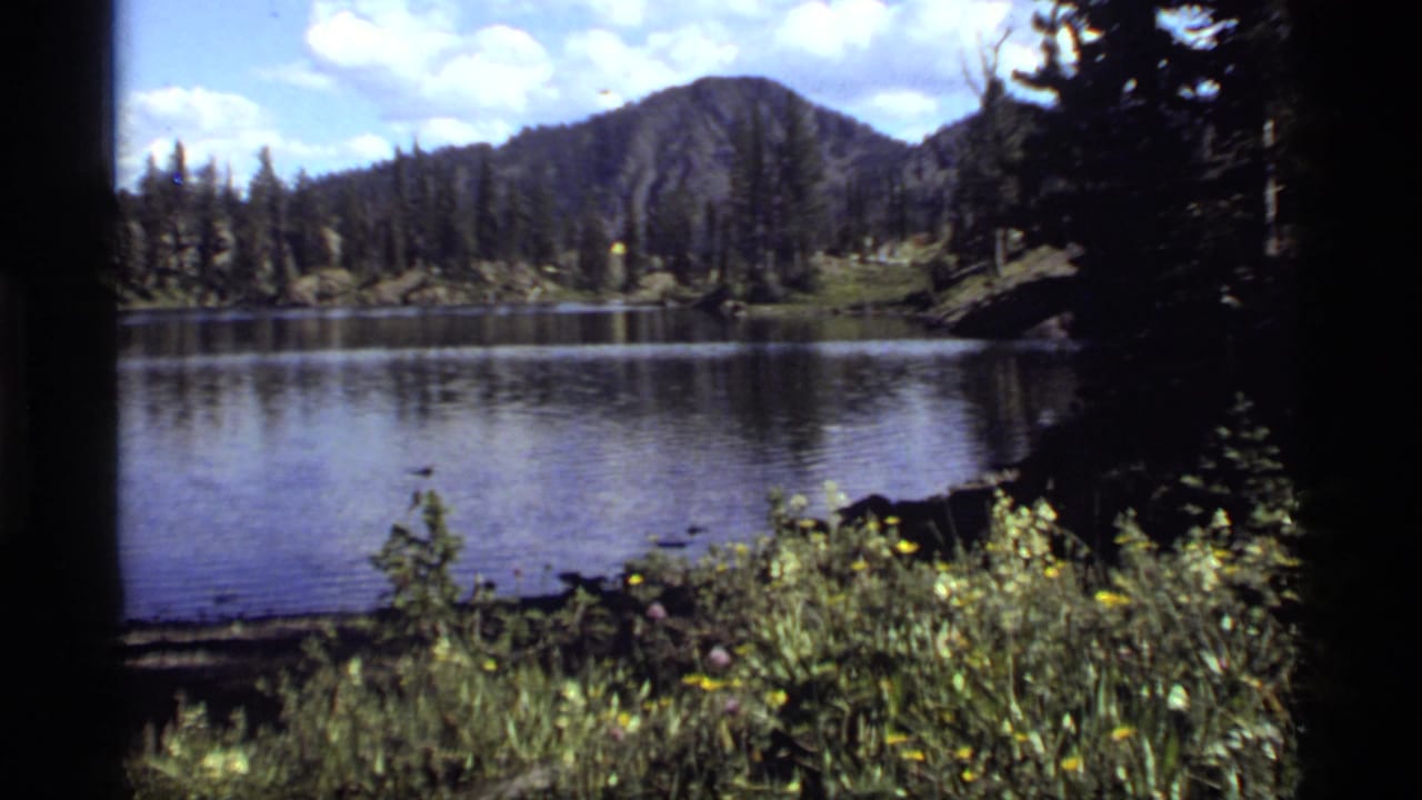 Sapphire Lake, Montana appears across the frame with a wooded shoreline, mountain backdrop, and 8mm edge shadowing.
