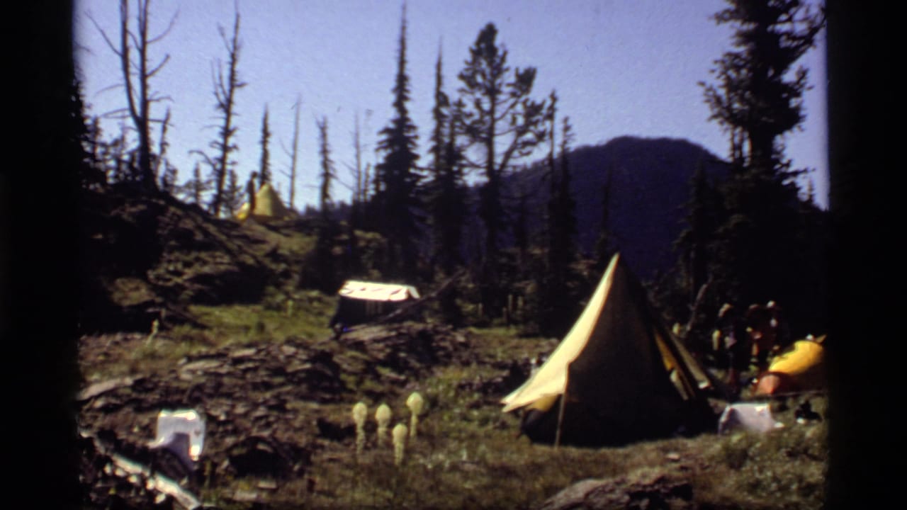 Mountain campsite with canvas tents, rope line, yellow marker, pine trees, and small figures.