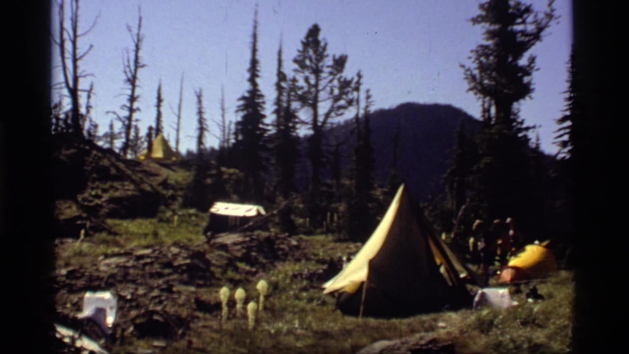 Sapphire Lake, Montana campsite scene with a yellow marker, rope line, canvas shelters, pine trees, and small people near camp.
