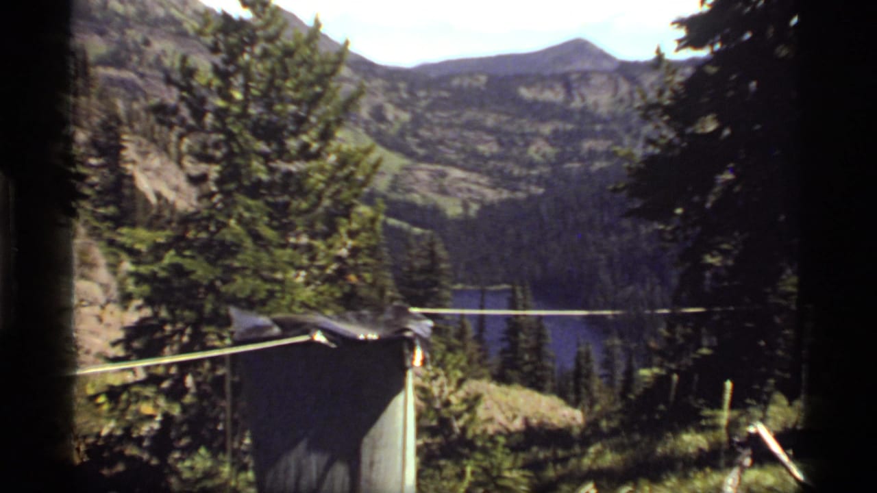 Sapphire Lake, Montana appears beyond evergreens and campsite gear, with a rope or clothesline stretching across the frame.