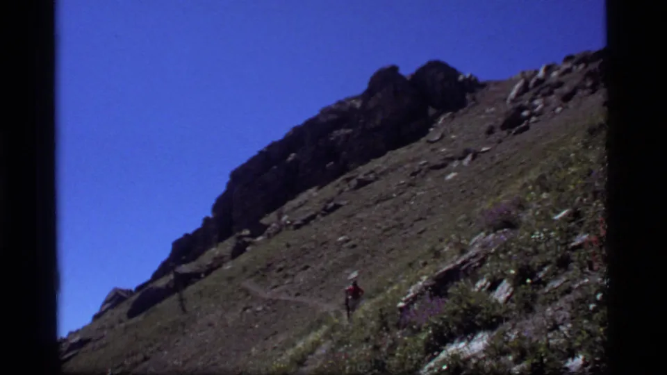 1977 home-movie view of a hiker crossing a rugged Montana mountainside near Sapphire Lake.