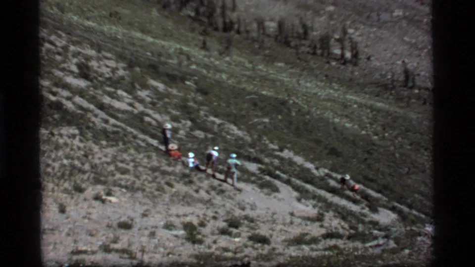 A distant group of hikers appears on rugged Sapphire Lake mountain terrain in 1977 home-movie footage.