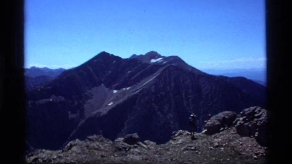 Wide 8mm view of high mountain peaks near Sapphire Lake, Montana, with a rocky foreground and saturated blue sky.