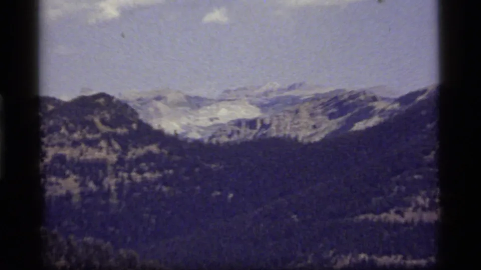 Final 1977 8mm view near Sapphire Lake, Montana, looking over a forested valley toward pale distant mountain ridges.