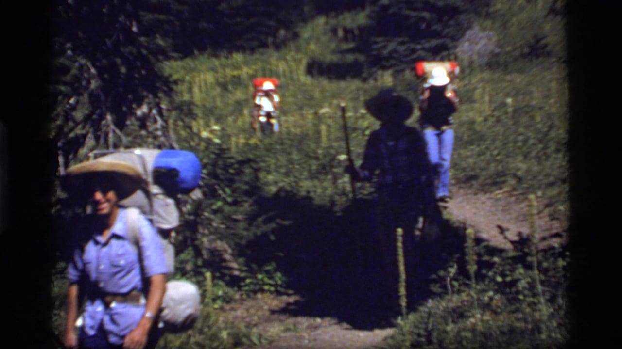 Hikers on a Sapphire Lake forest path appear in soft 8mm color, with backpacks and hats visible.