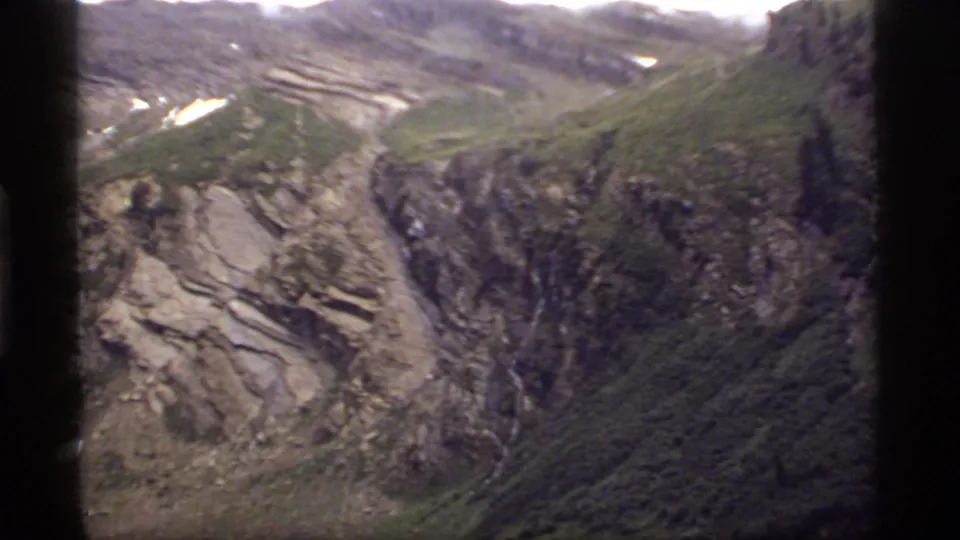 Rocky alpine slopes near Sapphire Lake, Montana, with snow patches and a thin waterfall in 1977 8mm footage.