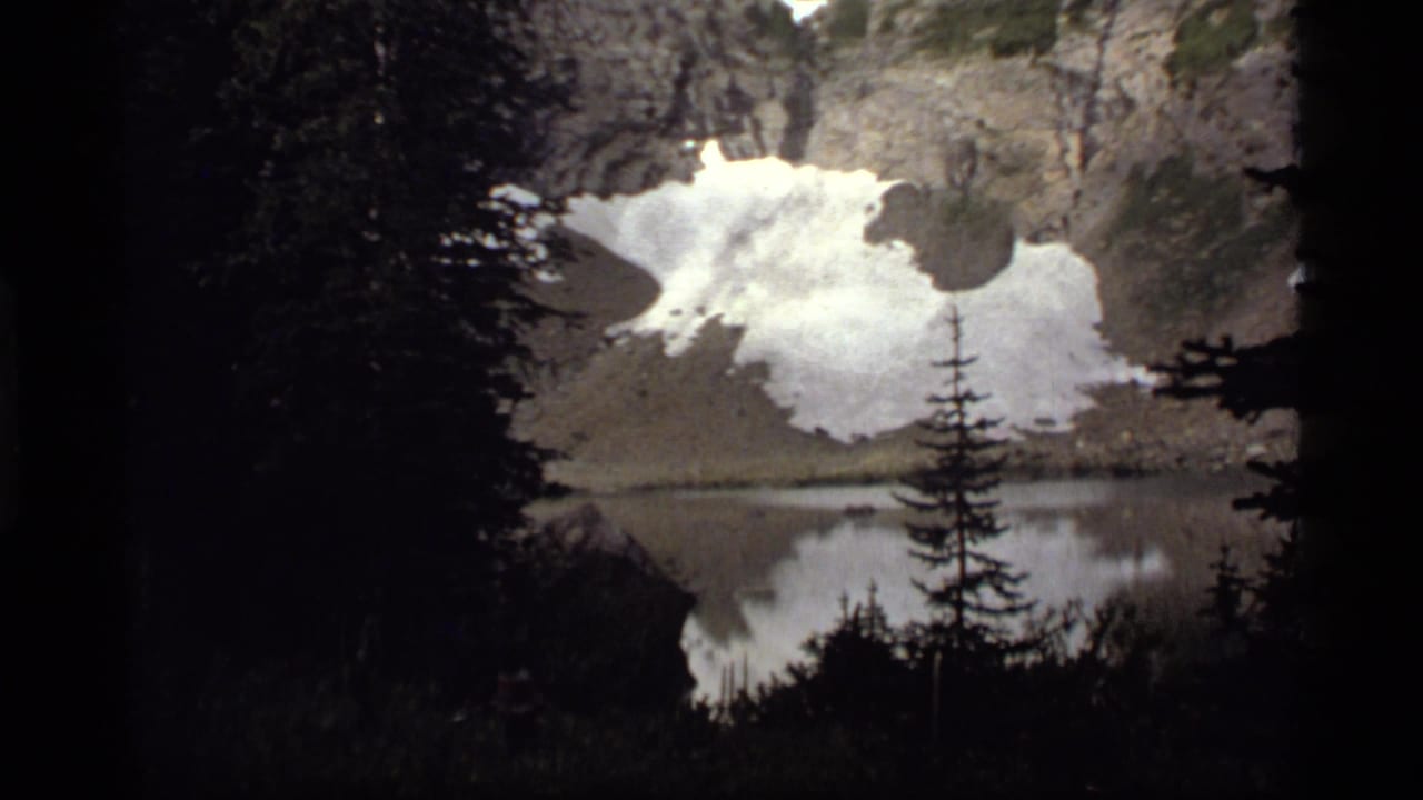 A second 1977 Sapphire Lake view holds on snow-dusted rock, dark conifers, and a soft reflection across the calm lake surface.