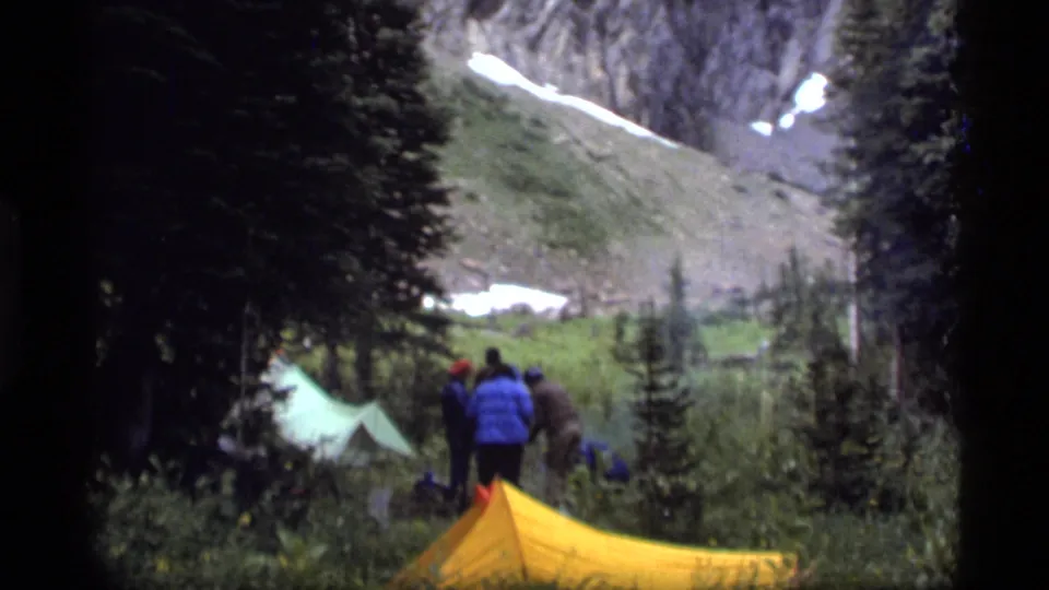 Campers at Sapphire Lake, Montana, appear to set up or adjust gear beside tents in a 1977 8mm home-movie frame.