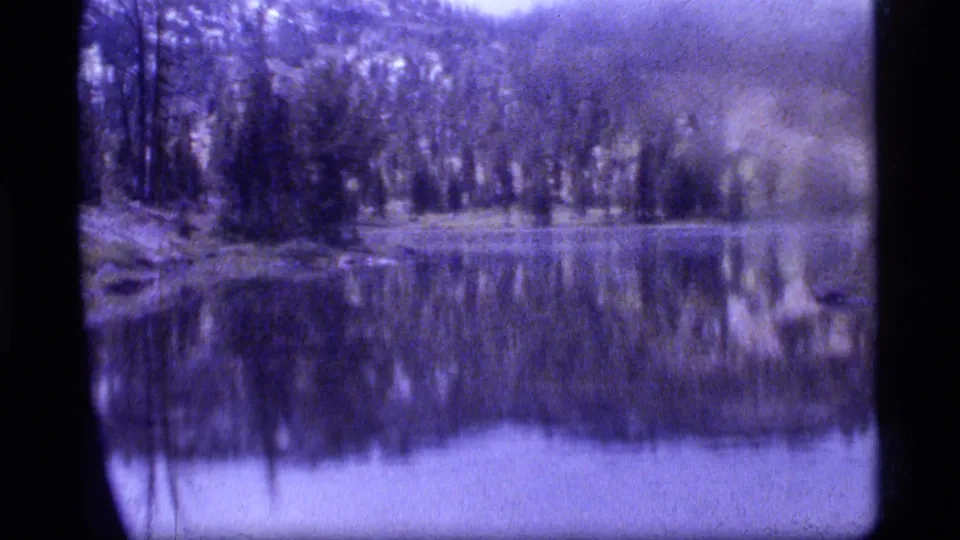 Sapphire Lake, Montana, in 1977 home-movie footage, with trees and shoreline reflected in calm water.