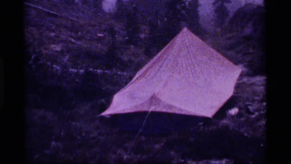 Red tent pitched in a damp forest clearing at Sapphire Lake, Montana, in 1977 home-movie footage.