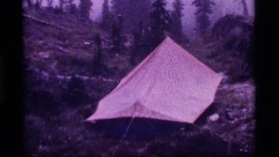 Closer 1977 8mm view of a red tent in a wet Montana forest clearing near Sapphire Lake.