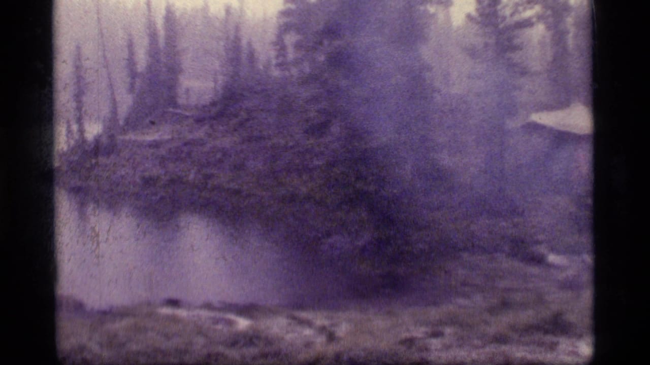 1977 8mm frame from Sapphire Lake, Montana, showing a misty lakeside campsite with a tent among conifers during rain.