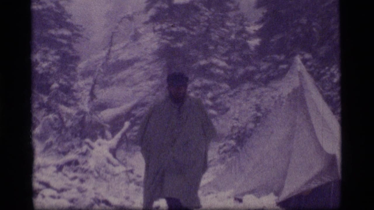 1977 Sapphire Lake, Montana 8mm frame showing a lone camper near a small tent among snow-covered evergreens.