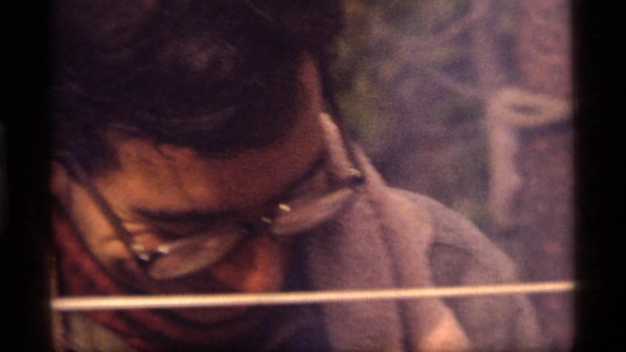 Man with thick glasses looks downward beside a pale horizontal line.
