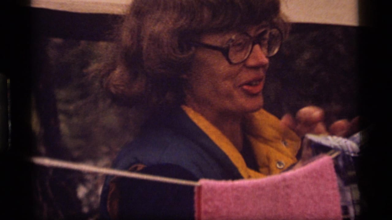 In 1977 Sapphire Lake home-movie footage, a woman with glasses stands beside hanging laundry on a clothesline.