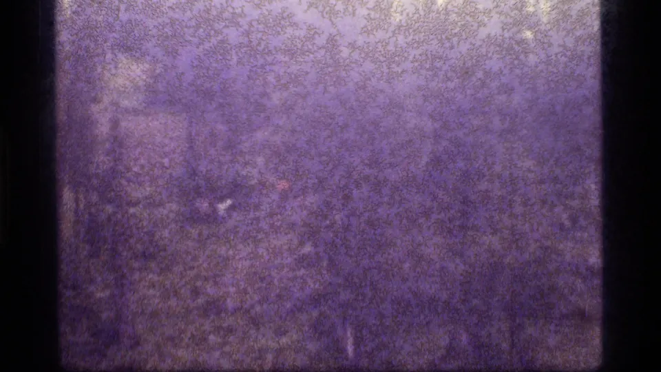 1977 Sapphire Lake, Montana 8mm frame with dense purple grain, dark edge banding, and indistinct remote landscape detail.