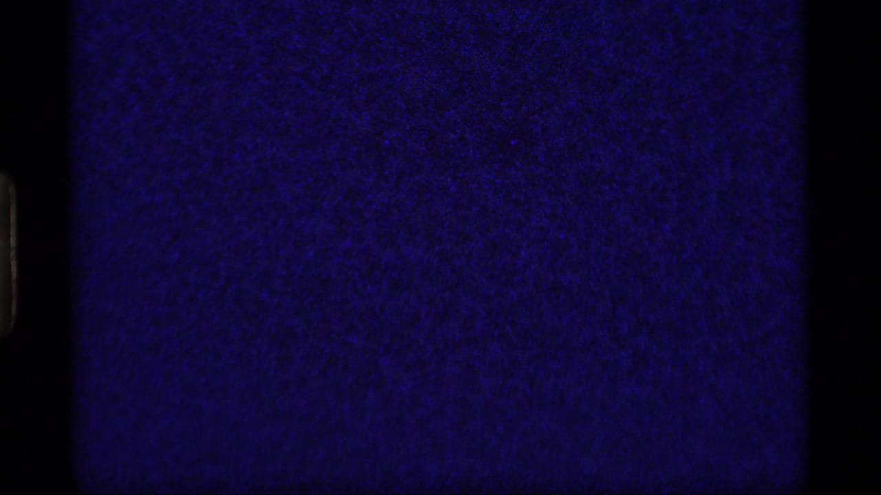 Dark blue film exposure area beside a small forest frame with a man bending near the ground.