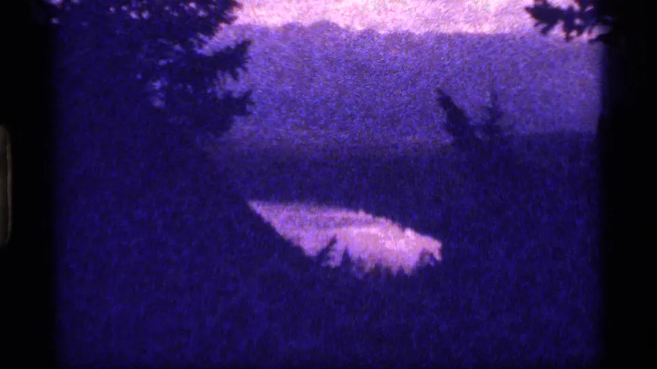 A wide twilight 8mm frame near Sapphire Lake, Montana, appears to show dark water framed by trees with a pale reflective shape near the lower center.